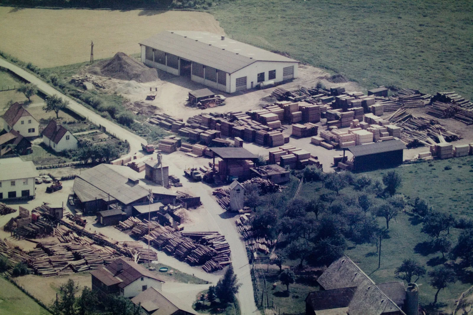Historisches Luftbild des Sägewerks mit Halle und Holzstapeln
